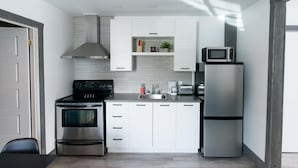 A modern kitchen with white cabinets, stainless steel appliances, and a built-in microwave. - Loft with bed and sofabed in the city centre (Le Court-toit) (Rouyn-Noranda)