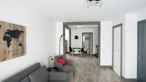 A modern living room with a gray sofa, a world map artwork, and a dining area in the background. - Loft with bed and sofabed in the city centre (Le Court-toit) (Rouyn-Noranda)
