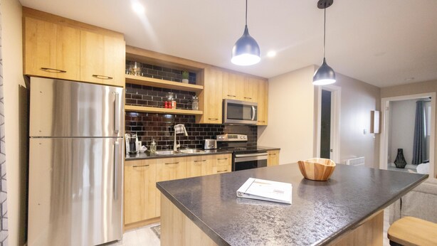 Una cocina moderna con electrodomésticos de acero inoxidable, armarios de madera y encimera de granito.