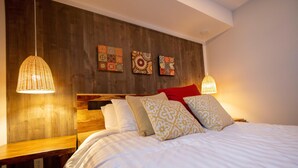 Una cama bien hecha con almohadas estampadas, cabecera de madera y dos lámparas colgantes.
