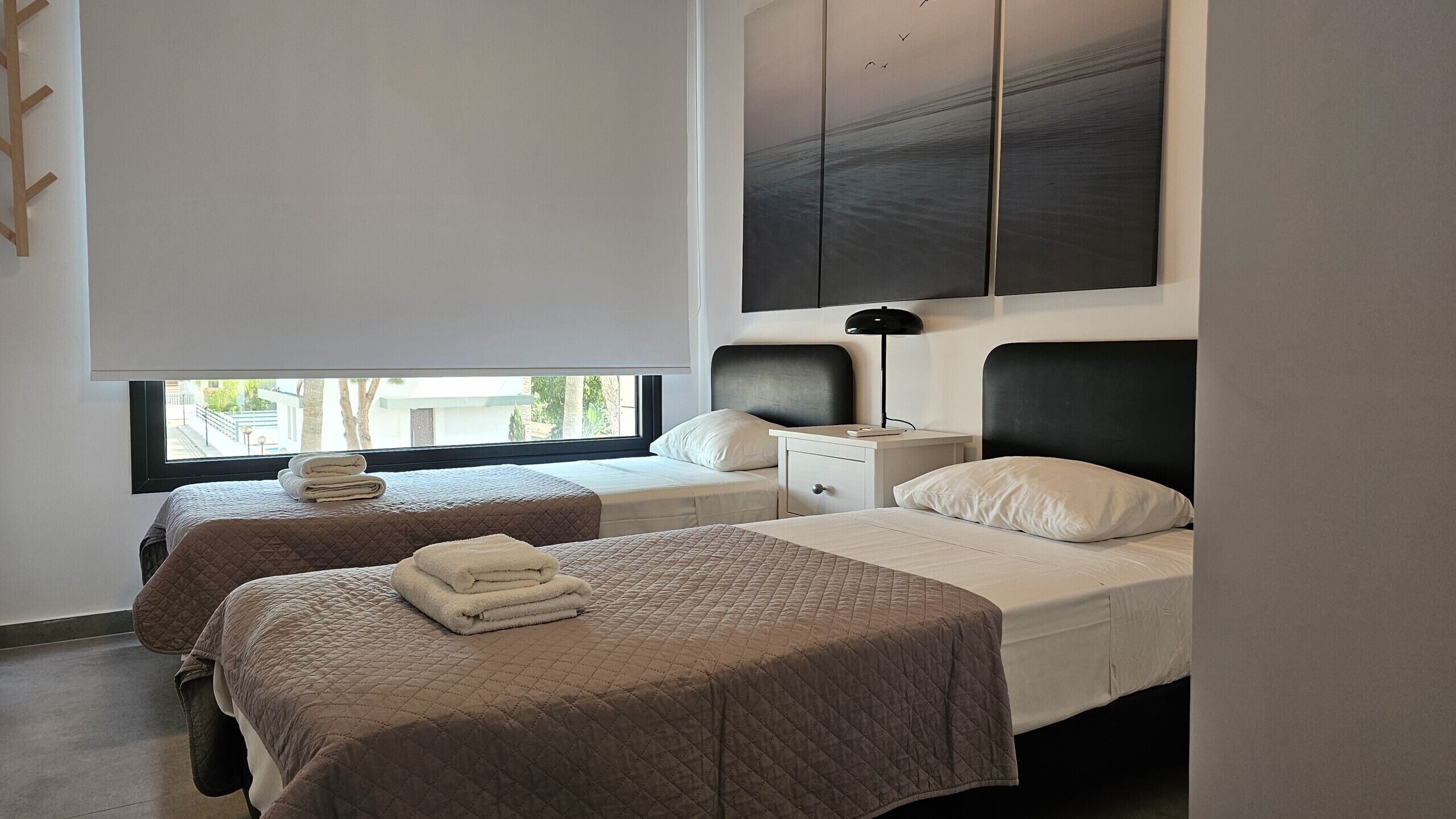 Ein modernes Hotelzimmer mit zwei Betten, einem großen Fenster und Blick ins Freie.