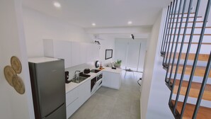 Une cuisine moderne avec des meubles blancs, un réfrigérateur Bosch et un petit îlot central doté d’un évier.