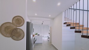 Une cuisine moderne équipée d’un réfrigérateur, d’un coin repas avec un banc et d’un escalier avec des marches en bois.