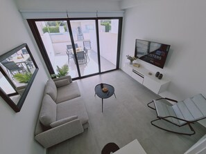 A modern living room with a sofa, a coffee table, and a TV on a white wall.
