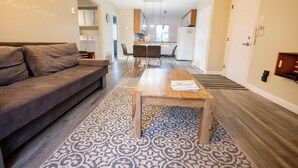 Una sala de estar moderna con un sofá, una mesa de centro de madera y alfombras estampadas.