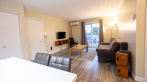 Una sala de estar con sofá, mesa de centro, televisor y mesa de comedor.