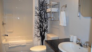 A bathroom with a bathtub, toilet, sink, and a decorative tree. - Suite with closed bedroom and sofa bed on the rue Principale (Le Chic-urbain) (Rouyn-Noranda)