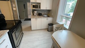A compact kitchen with white cabinets, a microwave, a coffee maker, and a sink.