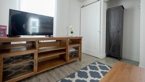 Ein Zimmer mit einer Holzunterhaltungsanlage, einem Flachbildfernseher, einem kleinen Tisch und einem dunklen Holzschrank.