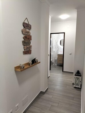 Un pasillo con un letrero de madera que dice “Live Dream Work Imagine Laugh LOVE” y una estantería con pequeñas figuras.