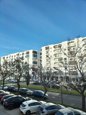 Un edificio residencial de varios pisos con balcones y un estacionamiento con distintos vehículos.