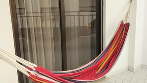 A room with a sliding glass door, a hammock, and a tiled floor.