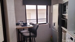 A compact kitchen with a dining area, a washing machine, and a refrigerator.
