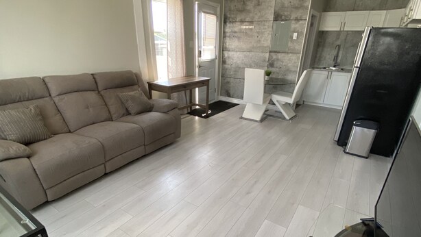 A modern living room with a beige sofa, a glass coffee table, and a black TV stand. - Two bedrooms flat in Rouyn (Le Cardinal) (Rouyn-Noranda)
