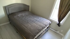 A bedroom with a bed, a window with curtains, and a radiator. - Two bedrooms flat in Rouyn (Le Cardinal) (Rouyn-Noranda)