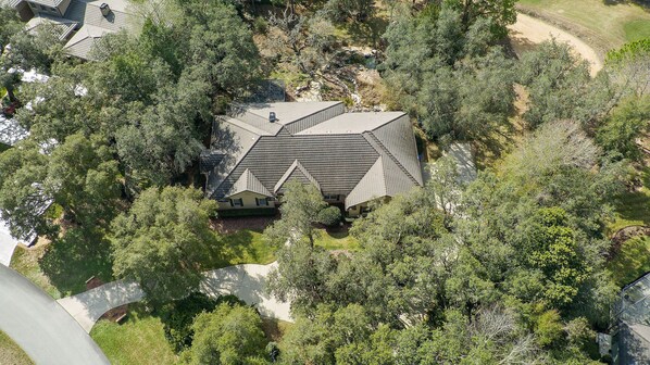 An aerial view of a house surrounded by dense trees, with a sloped roof and a visible satellite dish. - Private, tranquil 4 bed retreat near Crystal River (Lecanto)