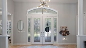 Un vestíbulo amplio con una puerta blanca grande, un espejo y un perchero.