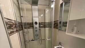 Une salle de bain compacte avec une douche à parois de verre, un lavabo blanc et des toilettes.