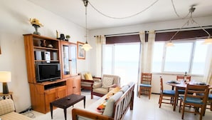 Un amplio salón con sofá, mesa de comedor y televisor.