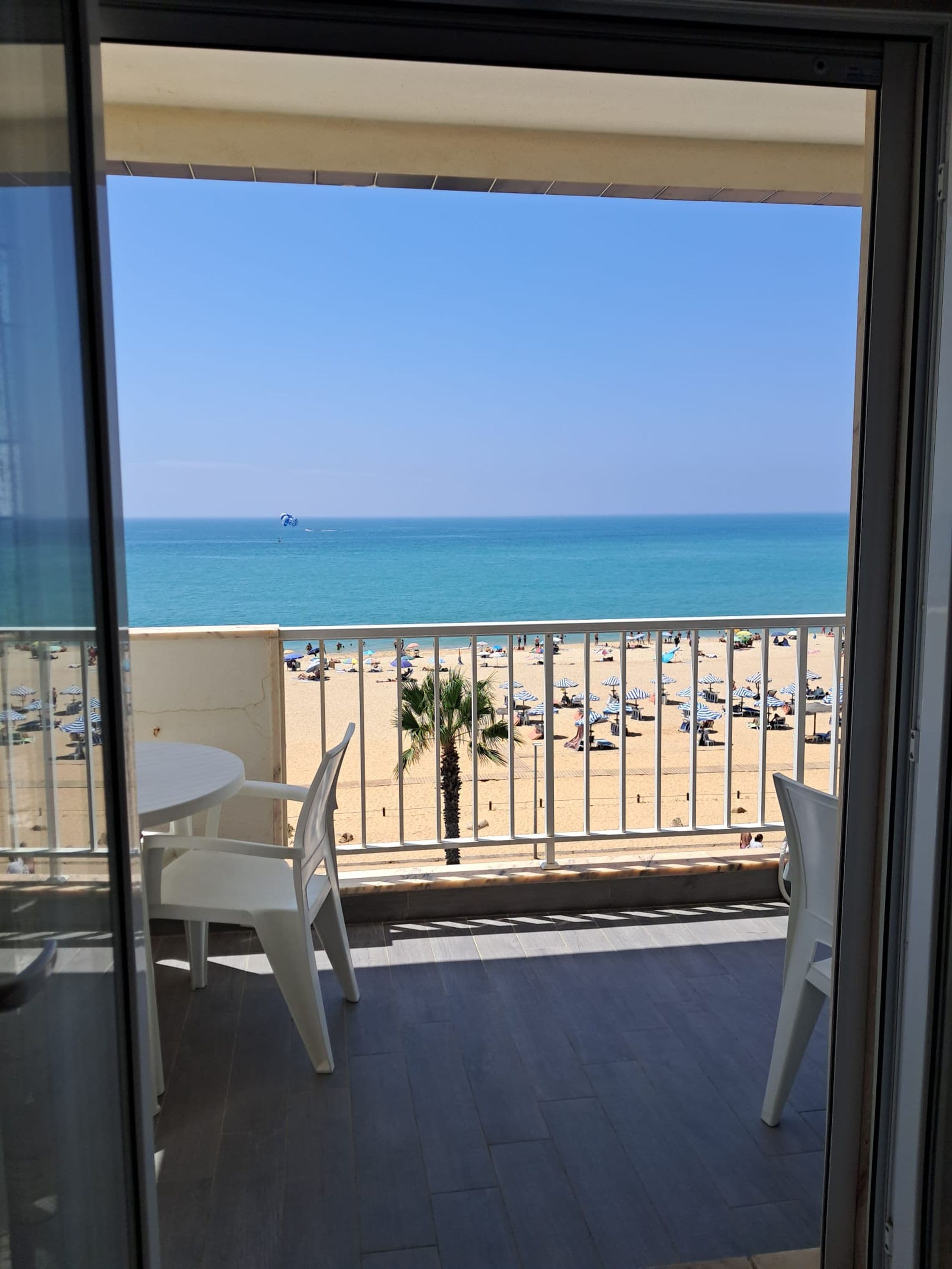 A balcony with a view of a beach and the sea.