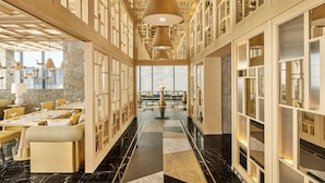 Een moderne hotel lobby met een centraal zithoek, hoge plafonds en een marmeren vloer.