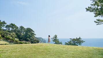 Guests can enjoy breathtaking ocean views from a serene hillside setting surrounded by lush trees and shrubs.