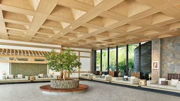 A spacious lobby with a high wooden ceiling, a central stone planter with a tree, and seating areas along the walls.