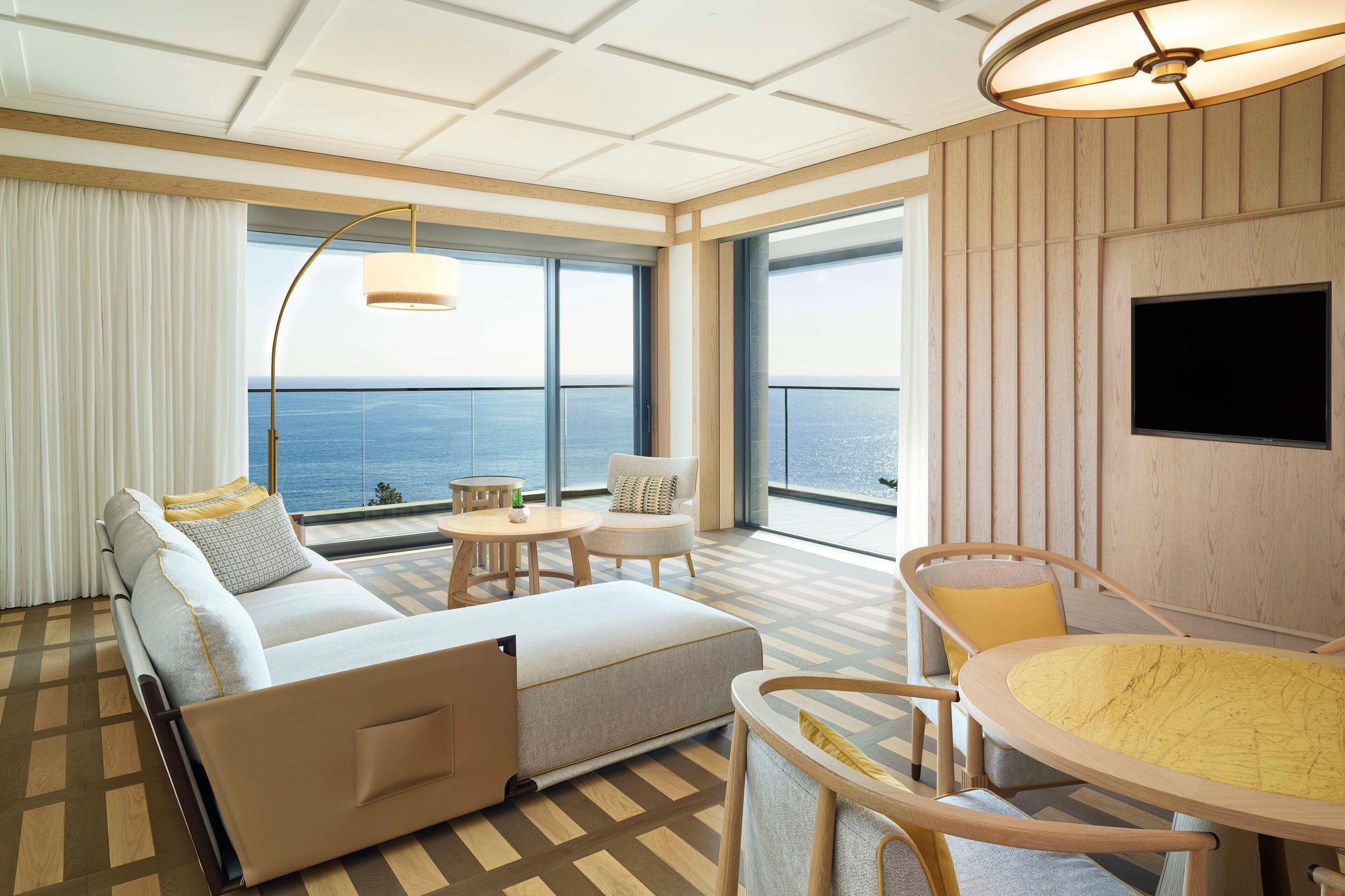 Une chambre d’hôtel moderne, équipée d’un canapé, d’une table ronde et d’un téléviseur fixé au mur.