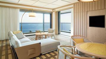 Une chambre d’hôtel moderne, équipée d’un canapé, d’une table ronde et d’un téléviseur fixé au mur.