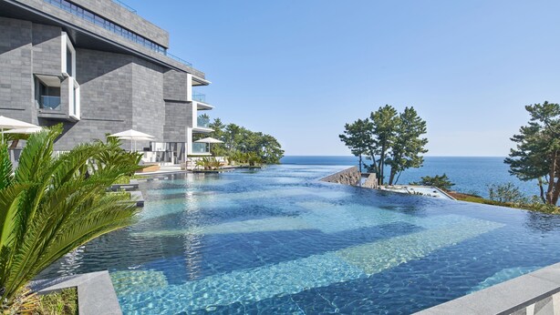 Een modern hotel met een overloopzwembad met uitzicht op de zee.