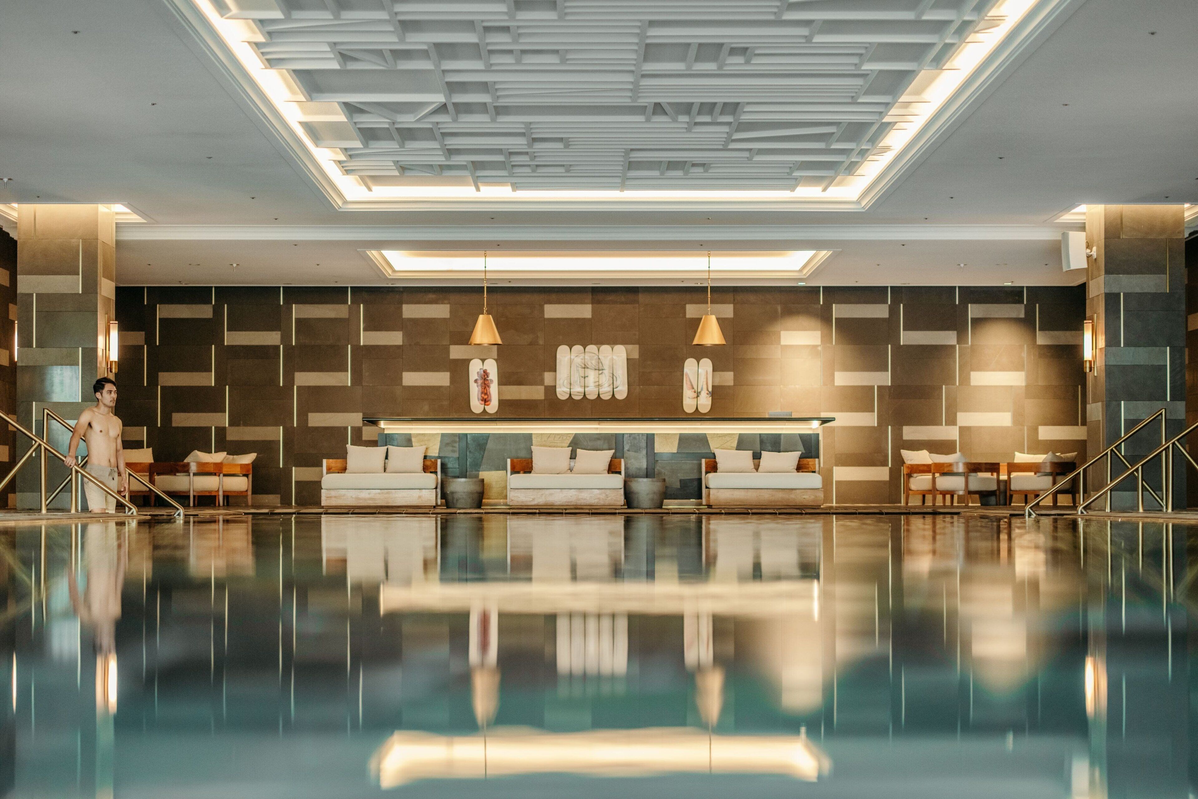 Un vestíbulo moderno con un estanque reflectante, un mostrador de recepción y una pared con diseño.