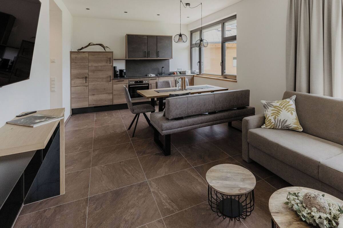A modern living room with a sofa, a coffee table, and a dining area with a table and chairs.