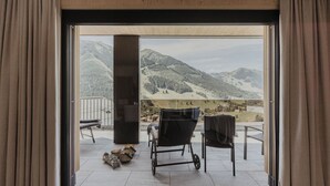 Ein Zimmer mit großem Fenster und Blick auf die Berge, inklusive Rollstuhl und einer Bank.