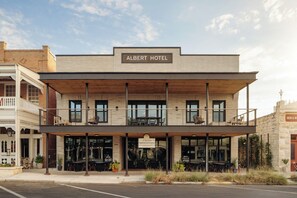 Un hotel con un cartel que dice 'Albert Hotel' y una tienda llamada 'Cross Mountain Vineyards' debajo.