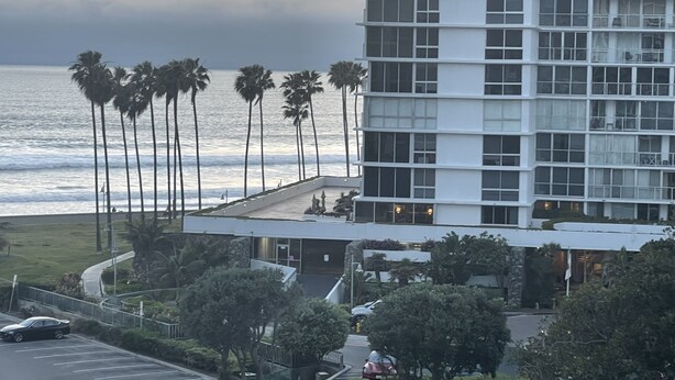 Ein modernes Hotel mit Blick auf den Ozean und Palmen.