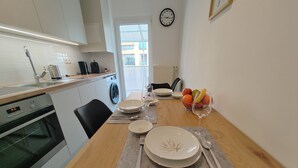 A modern kitchen with a dining area. It includes a sink, a washing machine, a clock, and a fruit bowl. - S15 Studio Apartment Zagreb Croatia-free Parking (Zagreb)