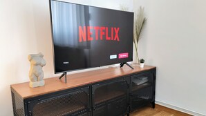A television on a wooden console with a mesh storage unit below. - S15 Studio Apartment Zagreb Croatia-free Parking (Zagreb)