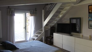 Une chambre à coucher avec un lit, une commode, un téléviseur et un escalier.