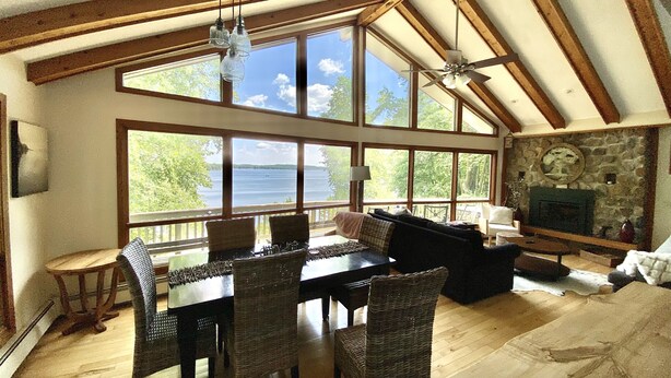 A spacious room with a large dining table, wicker chairs, and a stone fireplace.