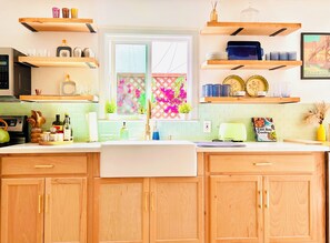 Una cocina con armarios de madera, un microondas, un tostador y varios utensilios de cocina en las estanterías.