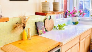 A kitchen with a dishwasher, wooden cabinets, a tiled backsplash, a framed picture, and a window with a view.