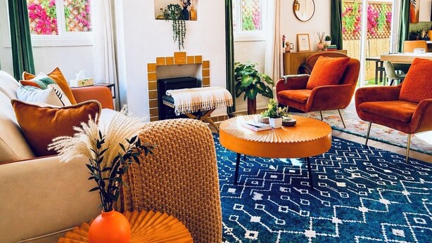 A living room with a sofa, armchair, coffee table, fireplace, and a patterned rug.