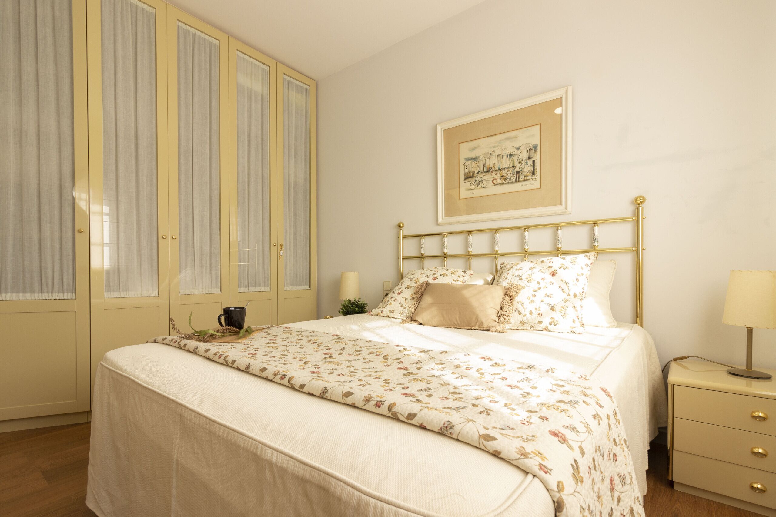 Een slaapkamer met een bed, nachtkastje, lamp, een inlijsting foto aan de muur, en een garderobe met gordijnen.
