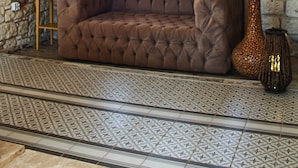 A room with a tufted sofa, a chandelier, a blue door, and a patterned floor. - Alaçatı Viola Hotel (Çesme)