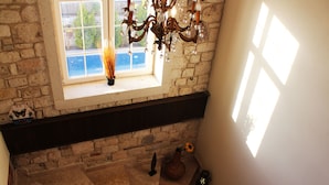 A stone wall, a window with a view, a chandelier, and a vase with a sunflower. - Alaçatı Viola Hotel (Çesme)