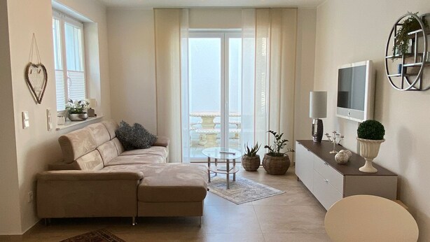 Una sala de estar moderna con un sofá, una mesa de centro y un televisor. Cuenta con un balcón con vistas.