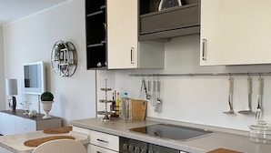 Una cocina moderna con armarios blancos, horno integrado y encimera de granito.