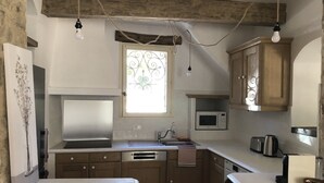 A kitchen with wooden cabinets, a built-in microwave, a sink, and a washing machine. - New! Renovated cottage in old mill with swimming pool (Forcalquier)