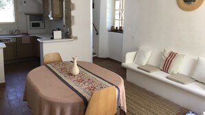 A cozy living area with a dining table, a sofa, and a kitchen in the background. - New! Renovated cottage in old mill with swimming pool (Forcalquier)
