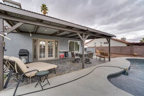 Un patio couvert avec des meubles d’extérieur, un barbecue et une piscine.